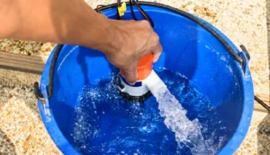 Bomba de achique para barco que evacúa agua mediante una manguera de descarga.