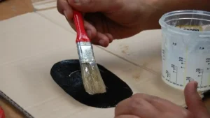 Aplicación de pegamento con un pincel sobre un parche para reparar una neumática de PVC