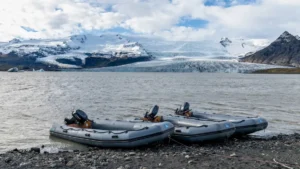 Embarcaciones semirrígidas grises junto a la orilla de un lago glaciar